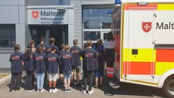 Eine Gruppe Malteser Schulsanitäter besichtigt einen Rettungswagen