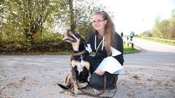 Malteser Besuchsdiensthelferin kniet neben Hund